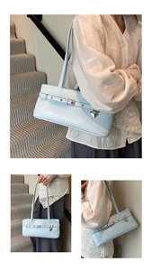 Detail view of light blue leather shoulder bag with buckle strap and heart pendant