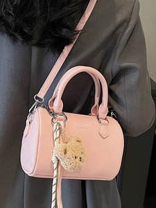 Pink pebbled leather Boston barrel bag with plush bear charm and adjustable strap
