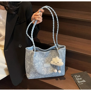 Detail of light blue floral tote bag with woven straps and plush cloud charm