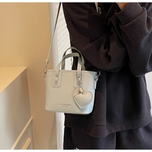 Detail of light blue bucket bag with lychee texture and heart-shaped pendant