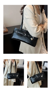 Detail view of glossy black leather underarm bag with silver heart pendant and metal buckle
