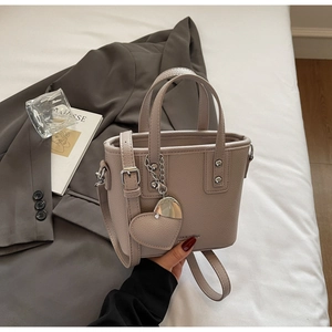 Detail of grey bucket bag showing high-quality lychee texture and heart-shaped leather charm