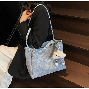 Close-up of light blue floral denim tote bag with leather tag and plush cloud charm