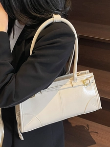 Minimalist beige glossy leather underarm bag with gold metal hardware on model