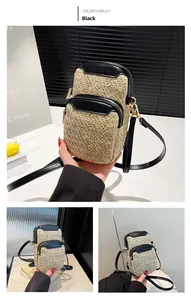 Detail of woven straw mini crossbody phone bag in black and beige with a wide strap