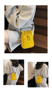 Detail view of yellow nylon crossbody bag with drawstring pocket and rope strap in lifestyle