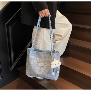 Detail of light blue floral tote bag with braided handles and cloud plush charm