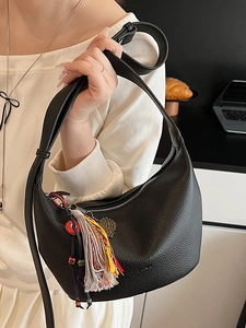 Sac croissant en cuir grainé noir avec des breloques à pompons et une bandoulière réglable