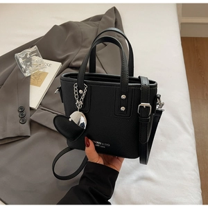 Detail of black lychee leather bucket bag with silver rivets and heart pendant