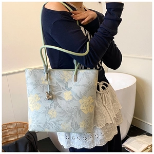 Detail of light green floral bucket bag with silver metal charm and elegant shoulder strap