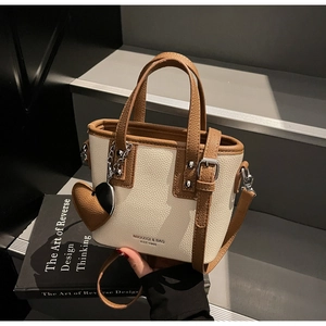 Close-up of contrast leather bucket bag with litchi grain and heart charm detail