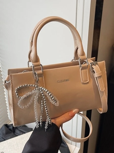 Minimalist beige leather tote bag with a decorative silver butterfly charm for women