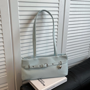 Detail of light mint green underarm bag with lychee texture and silver heart pendant