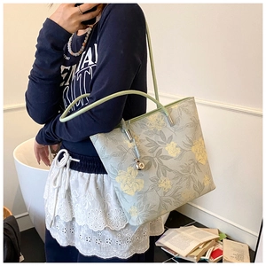 Detail of light blue floral bucket bag with green handles and vintage floral pattern