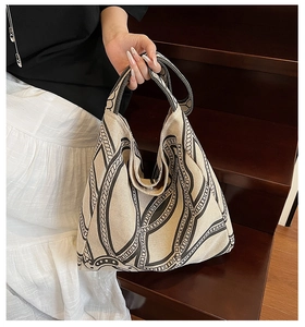 Close-up of cream canvas tote bag with black chain print on wooden stairs