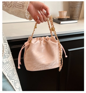 Detail of pink marble bucket bag with drawstring closure and golden chain strap