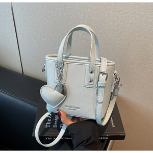 Close-up of light blue leather bucket bag with silver heart charm and brand logo