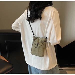 Close-up of military green nylon crossbody bag with drawstring pocket and striped strap