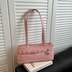 Detail of pink faux leather underarm bag featuring decorative strap and heart pendant