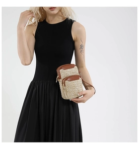 Detail of woven straw cell phone bag with brown leather trim and dual zipper texture