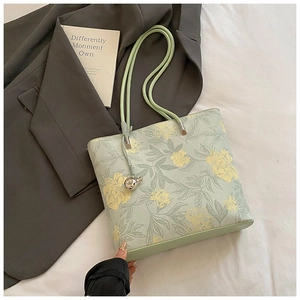 Detailed shot of floral bucket bag with green rope handles and silver sphere charm