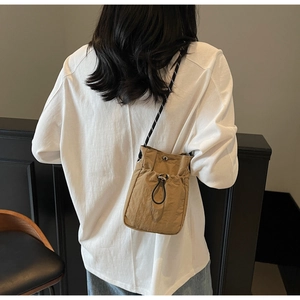 Detail view of khaki nylon bucket bag with drawstring closure and textured finish