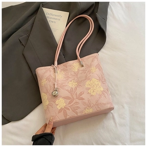 Detailed view of the pink floral bucket bag with silver bell charm on white fabric