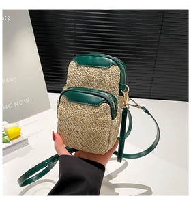 Detail of green leather and woven straw crossbody phone bag with double zipper