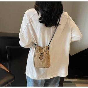 Close-up of khaki nylon drawstring phone bag with woven shoulder strap on a model
