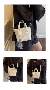 Detail of white embossed leather bucket bag featuring silver hardware and a grey tassel