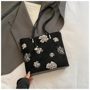 Detail of black fabric bucket bag with white floral embroidery and silver metal hardware