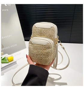 Detail of the woven mini phone bag with dual gold zippers and adjustable shoulder strap