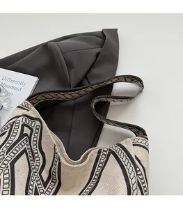 Detail view of the wide shoulder strap and woven texture on this beige tote bag
