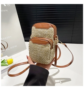 Close-up of woven crossbody phone bag with brown leather trim and zipper pocket detail