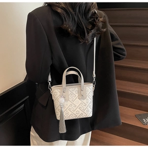 Detailed view of embroidery pattern and tassel on a stylish crossbody bucket bag