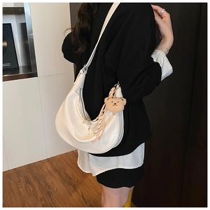 Detail view of cream hobo bag with crocodile texture and cute plush bear charm