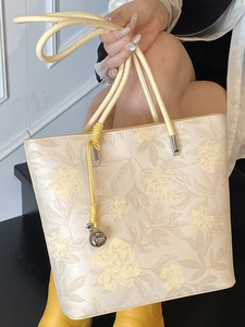 Floral bucket bag with yellow braided handles and silver ball charm accessory