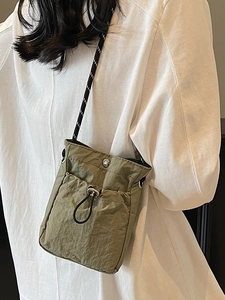 Minimalist olive green nylon crossbody bag with drawstring pocket and utility rope strap