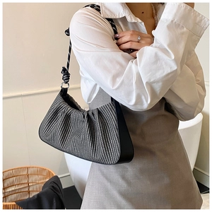 Detail of woven retro underarm bag with black and white texture and rope strap