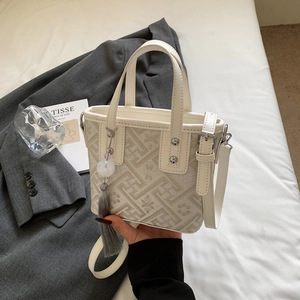 Detail of embroidered bucket bag featuring gray geometric patterns and tassel charm