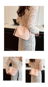 Detail of light pink drawstring bucket bag with gold chain strap on a lace dress