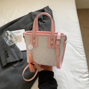 Detail of pink jacquard bucket bag with embroidery pattern and leather tassel charm