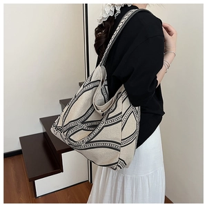 Detail of canvas tote bag showing black geometric chain print and wide shoulder strap