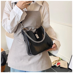 Detail einer schwarzen Lackledertasche mit silberner Kette und Metallschnalle