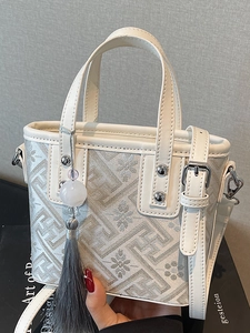 White jacquard bucket bag with floral embroidery, leather trim, and beaded tassel