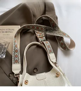 Detail of white crocodile pattern tote bag with bohemian colorful woven wide strap and rivets