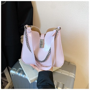 Detail der hellrosa Handtasche mit silbernem Drehverschluss und dekorativer dicker Kette