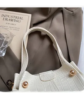 Detailed macro view of white crocodile pattern leather handbag with gold metal rivets