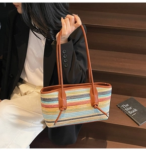 Detail of colorful woven straw tote bag with brown leather straps and knot accents