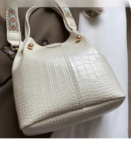 Detail of crocodile embossed beige bucket bag with stylish wide jacquard shoulder strap